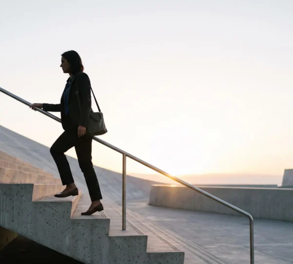 Silhouette d'un professionnel gravissant un escalier symbolique vers la lumière, illustrant la progression du niveau IV au niveau VI