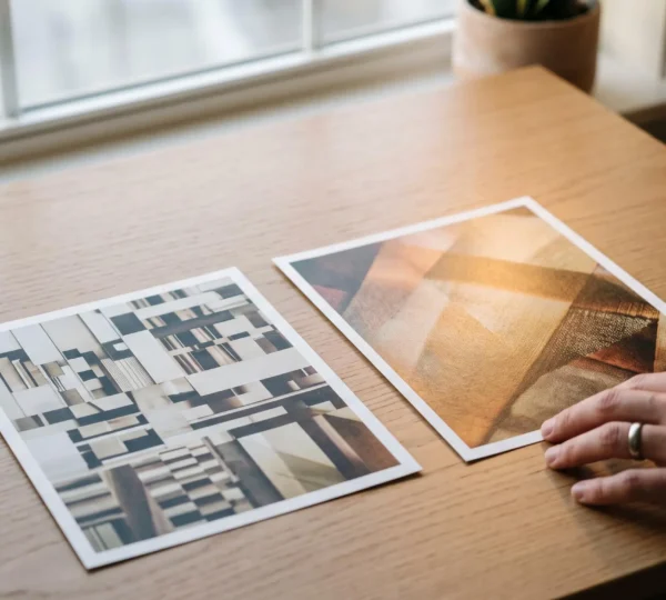 Deux tirages photographiques côte à côte sur une table en bois, l'un neutre et technique, l'autre habité par une lumière et une texture distinctives, symbolisant la transformation d'un style photographique